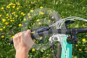 Woman cycling across a meadow full of blossoming yellow dandelions in spring