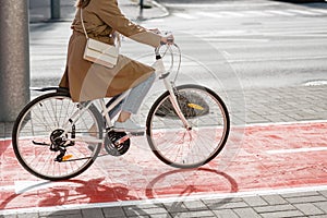 woman cycling along red bike lane road in city