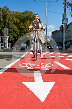 woman cycling along red bike lane road in city