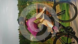 Woman cycling on bicycle at sunset. Cyclist training on bike. Vertical concept