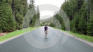 Woman cycling. Cyclist twists pedals on bicycle. Athlete training on bike in forest, preparing for bike race. Triathlon concept. S