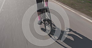 Woman cycling intensively on bike, close up. Cyclist legs on bicycle. Female riding on cycle. Triathlete training. Girl legs are p