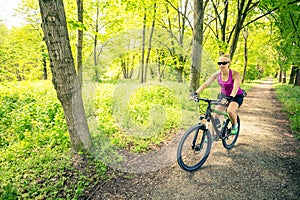Woman cycling a mountain bike in city park, summer day