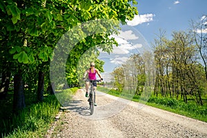 Woman cycling a mountain bike in city park, summer day