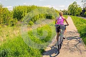 Woman cycling a mountain bike in city park, summer day