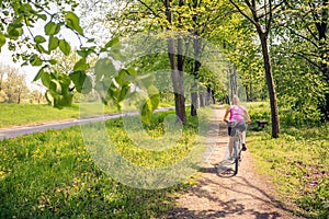 Woman cycling a mountain bike in city park, summer day