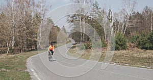 Woman cycling uphill. Female in helmet riding on bike. Athlete rides outdoor. Sportive girl training on bicycle. Cyclist pedaling
