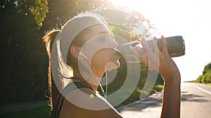 Woman cyclist drinks water after a workout