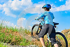 Woman cyclist pushing her bike up a steep slope