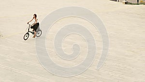 Woman cyclist riding a bike on paved road at square on summer day