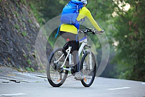 Woman cyclist riding mountain bike on forest trail