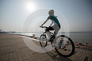 woman cyclist riding mountain bike on seaside