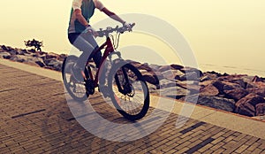 Woman Cyclist Riding Mountain Bike on seaside road