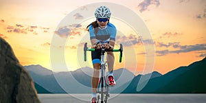 Woman Cyclist Riding Road Bike in the Beautiful Mountains at Sunset. Adventure, Healthy Lifestyle, Sport