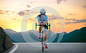 Woman Cyclist Riding Road Bike in the Beautiful Mountains at Sunset. Adventure, Healthy Lifestyle, Sport