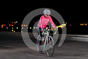 Woman Cyclist Riding Road Bike at Night in the City. Healthy Lifestyle and Urban Sport Concept