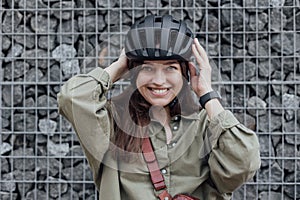 Woman cyclist stand with bicycle near stone wall in urban street