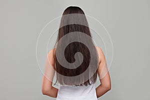 Woman with damaged hair before treatment on light grey background, back view