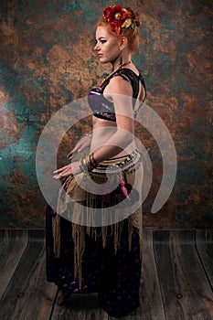 Woman in dance costume in red circlet of flowers looking away and holding hands near in tribal pose