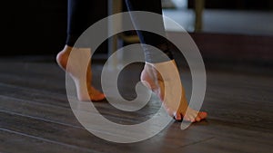 Woman dancer beautiful bare feet step on toes carefully on floor at ballet barre close view slow motion