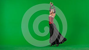 Woman dancer dancing on chroma key green screen. Female in flamenco style dress performs elegant spanish dance moves