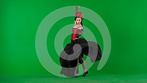 Woman dancer dancing on chroma key green screen. Female in flamenco style dress performs elegant spanish dance moves