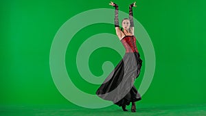 Woman dancer dancing on chroma key green screen. Female in flamenco style dress performs elegant spanish dance moves