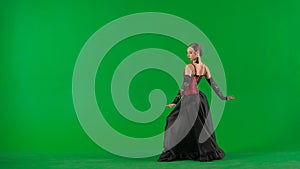 Woman dancer dancing on chroma key green screen. Female in flamenco style dress performs elegant spanish dance moves