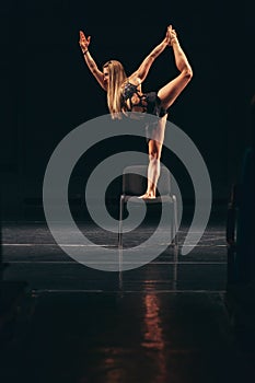 Woman dancer standing on chair during performance