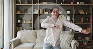 Woman dancing alone indoor listens favourite music through wireless earphones