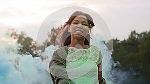 Woman dancing with colored smoke bombs