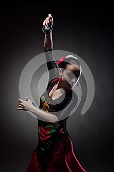Woman dancing flamenco with castanets on black photo