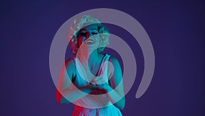 Woman dancing, having fun, sending air kiss. Woman in the look of Marilyn Monroe dancing in multicolored neon light in