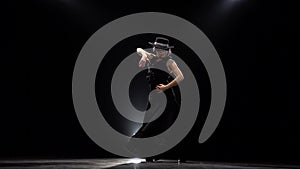 Woman dancing a incendiary dance. Black background. Llight from behind