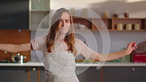 Woman dancing on kitchen. Lady gesturing with whisker in hand at kitchen