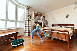 Woman is dancing with a mop.