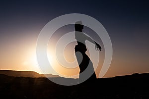 Woman dancing to the famous Arab belly dance. With sunset in the arid desert plain of Namibe. Africa. Angola
