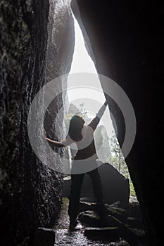 Woman in the dark cave with flaslight. back view. scenist girl between stones wall.