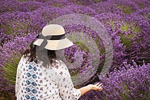 Woman with Dark Curly Hair Wearing a Sun Hat in a Purple Lavender Field