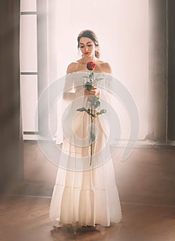 woman dark hair bare shoulders long white vintage dress. red rose in hands