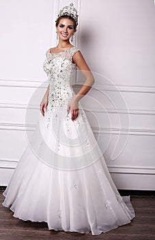 Woman with dark hair in luxurious wedding dress and precious crown