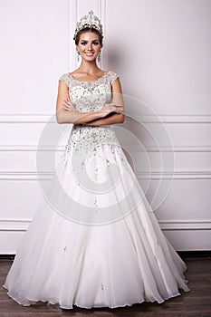 Woman with dark hair in luxurious wedding dress and precious crown
