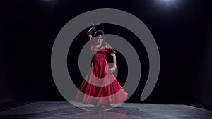 Woman in the dark room performs elegant movements dance. Black background