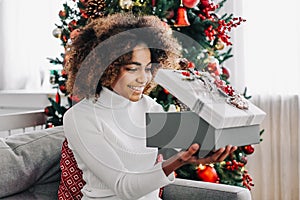 Woman with dark skin and kinky hair opening present box