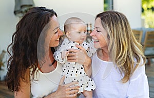 Woman with daughter and baby granddaughter resting outdoors in backyard.