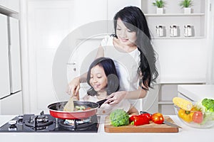 Woman and daughter cooking vegetable