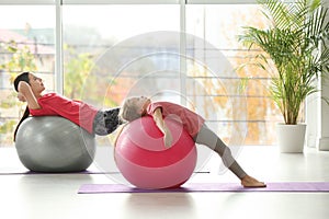 Woman and daughter doing exercise with fitness balls