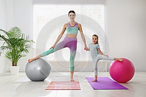 Woman and daughter doing exercise with fitness balls