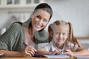 Woman and daughter drawing with felt-tip look at camera