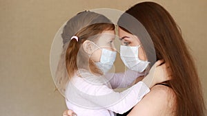 Woman and daughter in medical mask hugs. Kiss mother and baby. Health care and medical concept. Close up portrait. Virus